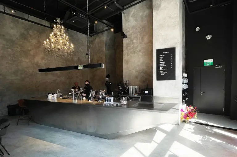 Moody interior of Alchemist The Mill Singapore with chandelier and minimalist coffee bar.