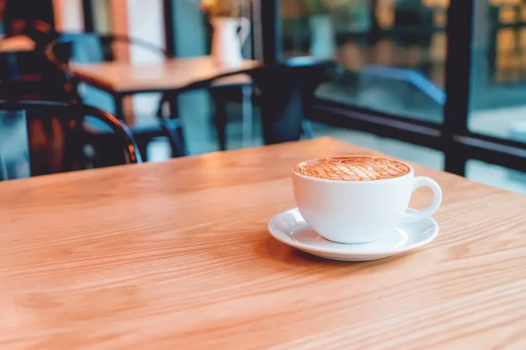 Latte coffee on wooden table in minimalist cafe setting Singapore