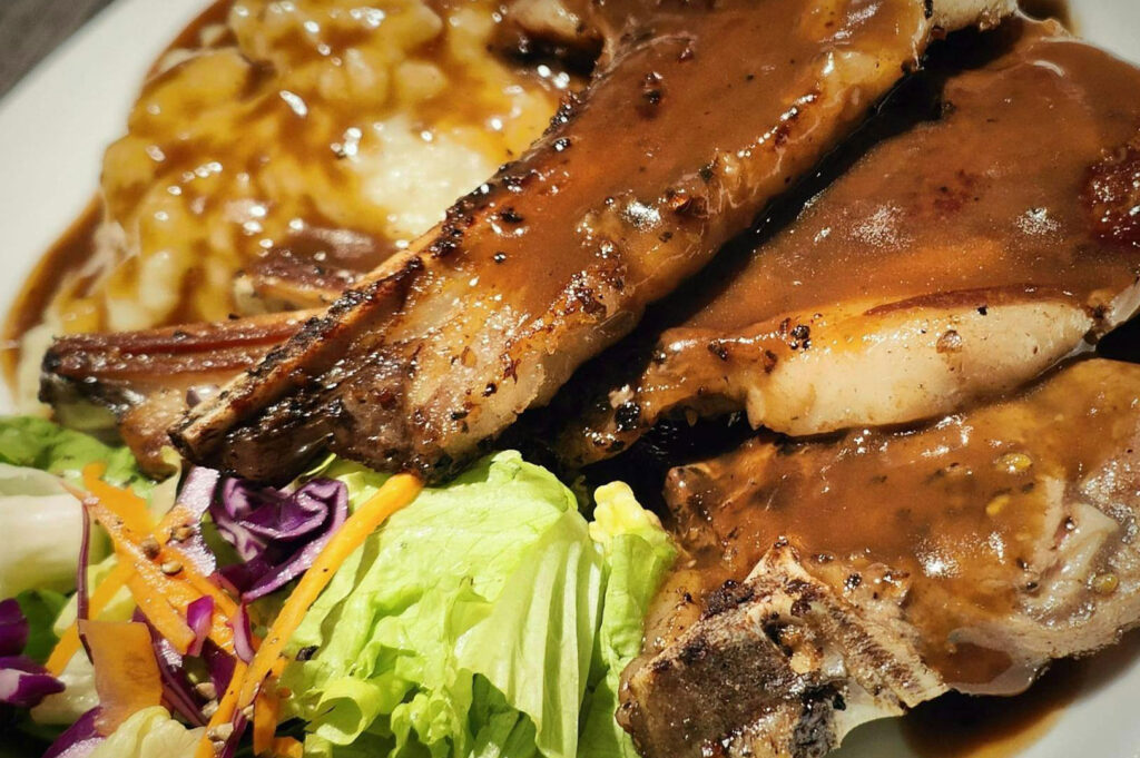 Grilled lamb chops with gravy, mashed potatoes, and salad.