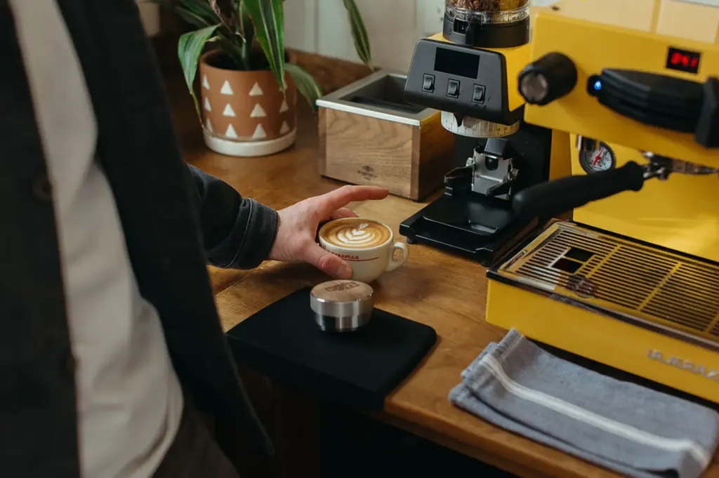 Barista preparing espresso at a cafe coffee station.