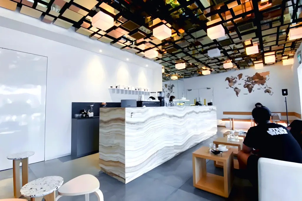 Fahrenheit Coffee Singapore interior featuring geometric mirrored ceiling design, marble counter, and modern minimalist cafe space