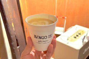 174BINGO Singapore coffee in paper cup with latte art held in hand showing minimalist takeaway coffee ritual and street side cafe experience