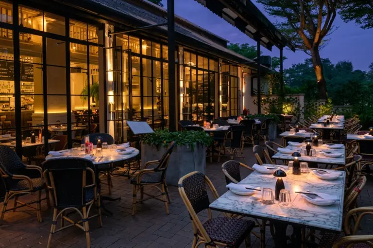 Restaurant patio at dusk with warm lighting and garden views