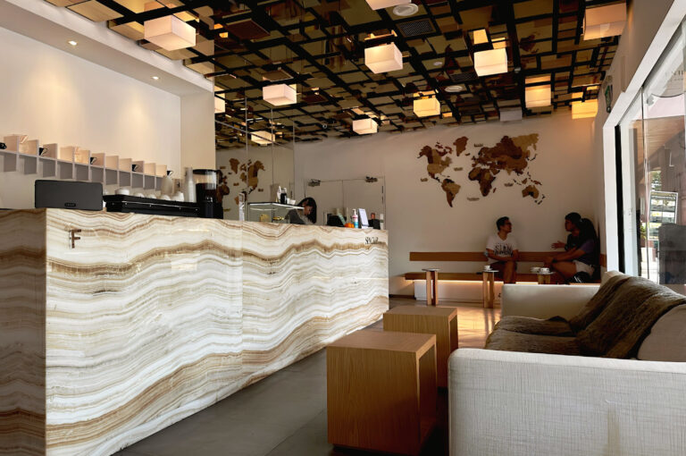 Modern minimalist cafe interior in Singapore with illuminated marble counter, geometric ceiling lights, and warm lounge seating atmosphere