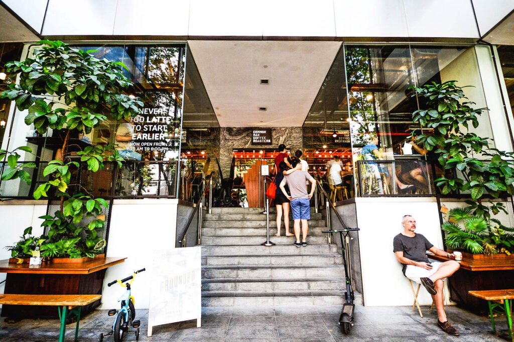 Common Man Coffee Roasters Martin Road Singapore exterior with glass facade, entrance steps, and people queuing outside busy cafe