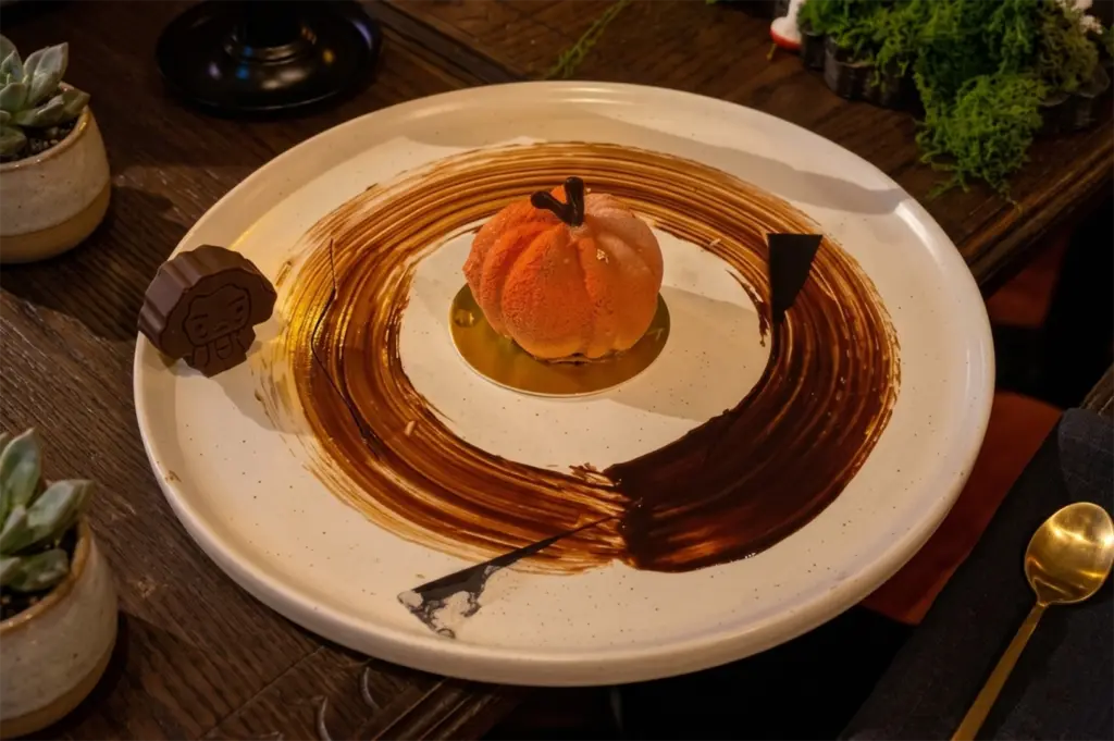 A gourmet pumpkin-shaped dessert plated with a chocolate swoosh on a rustic wooden table.