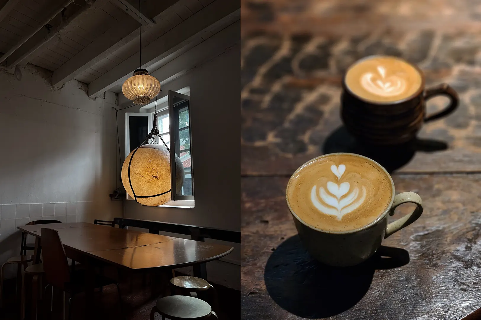 Minimalist cafe interior with pendant lights and dark table; two lattes with latte art on a wooden table.
