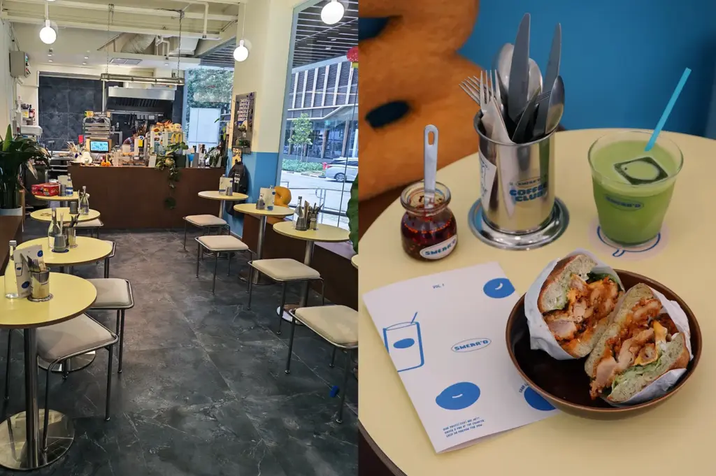 Cafe interior with empty tables beside a bagel sandwich, drink, and utensils on a tray.