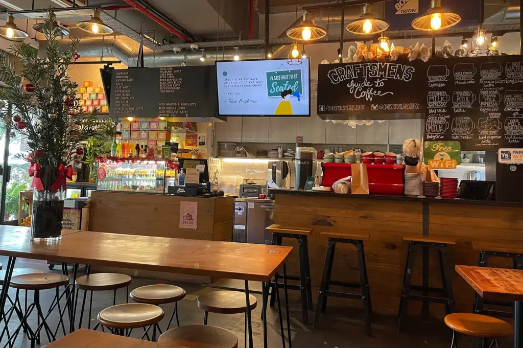 Craftsmen cafe interior with wooden tables, pendant lights, and chalkboard menu
